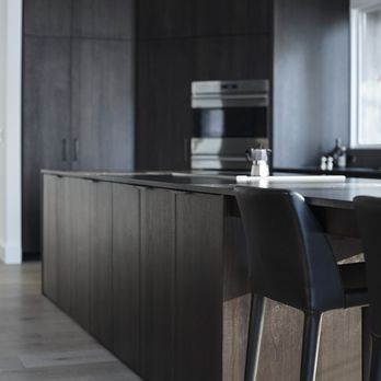 A modern kitchen with dark wooden cabinets and island, featuring minimalist design, built by Tycon Builders Inc. in San Francisco.